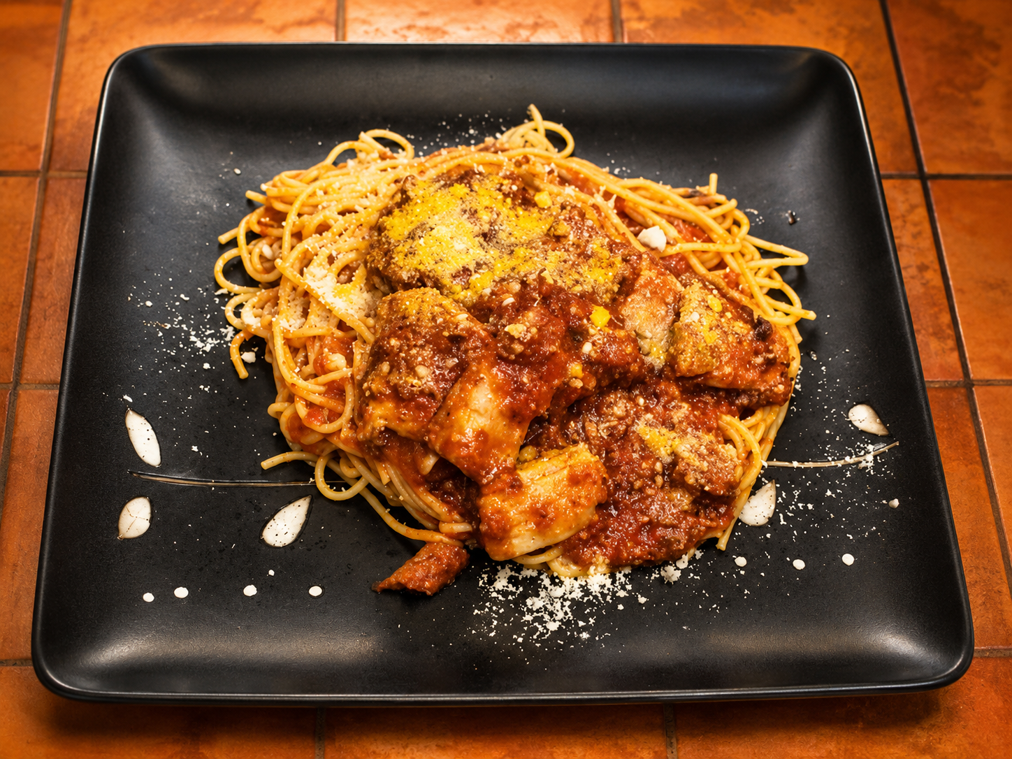 角皿に盛られた、肉入りトマトソースのスパゲッティ。粉チーズがふられている