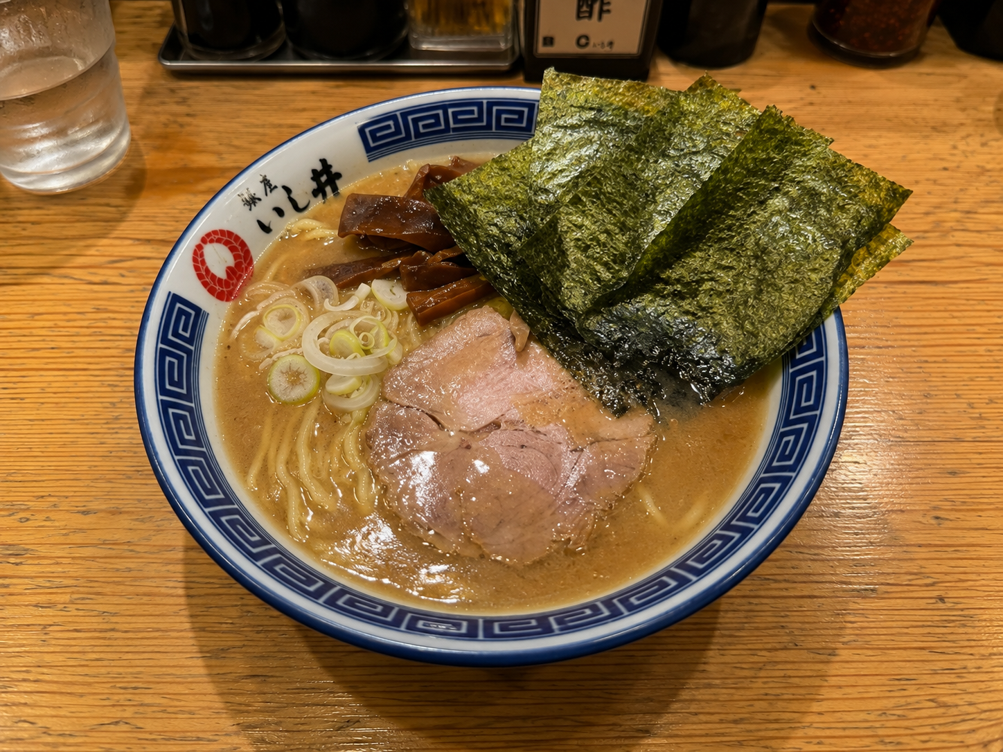 青い縁取りの器に盛られた汁ありのラーメン。チャーシュー、メンマ、刻みねぎ、海苔が乗っている