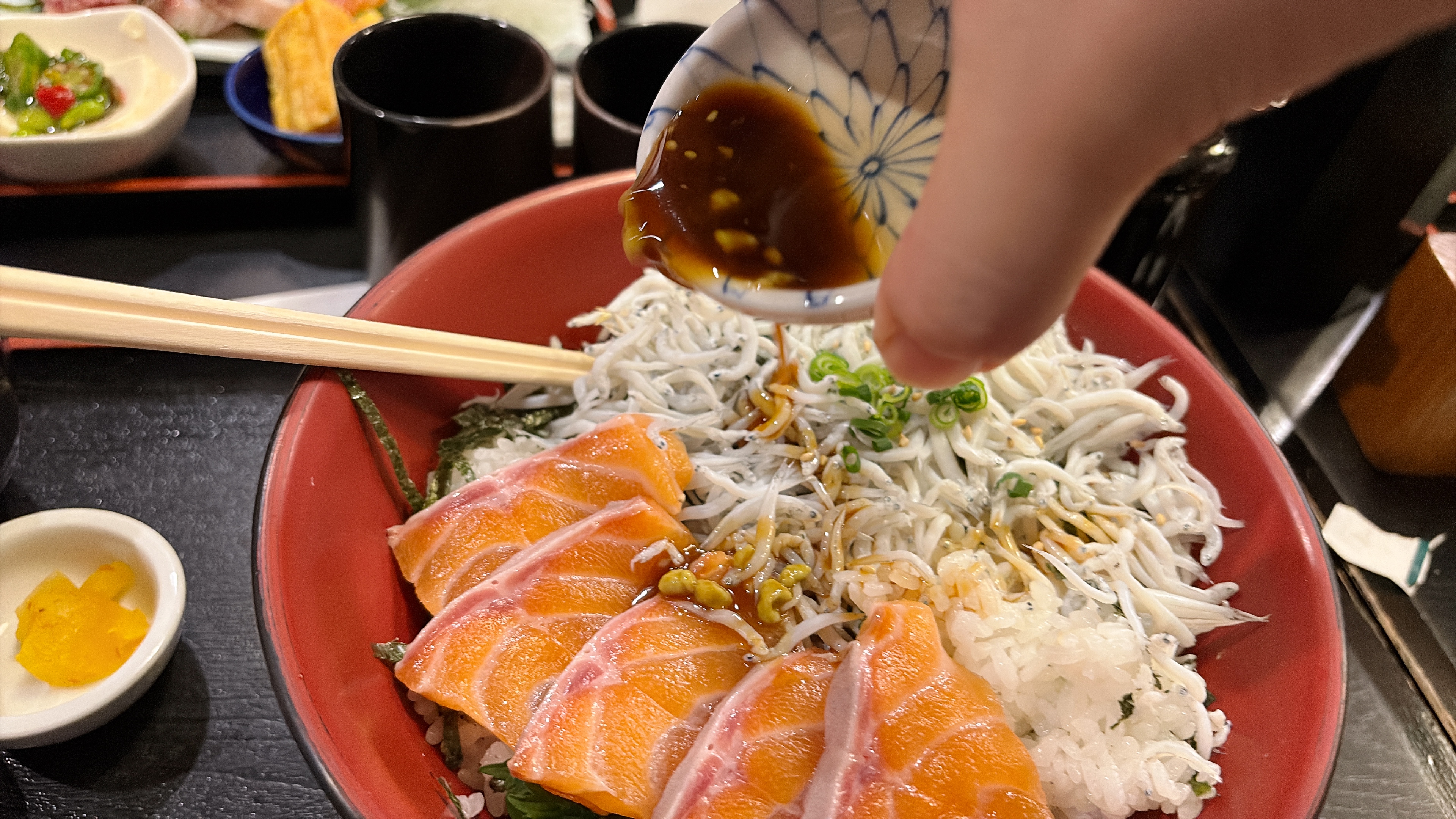 二品丼に醤油を回しかけている手元のシーン